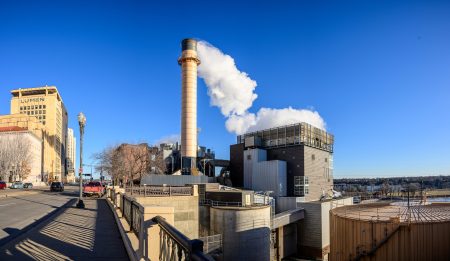 An industrial energy plant with steam blowing out of its main smokestack.
