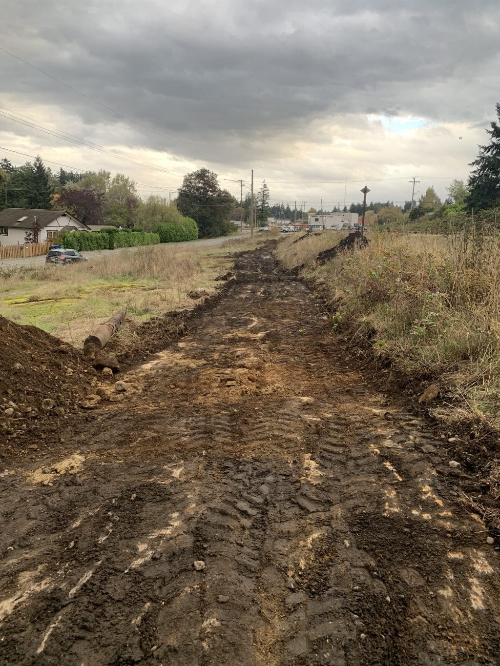 A cloudy sky above and a brown muddy path that has been recently carved out