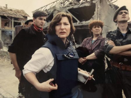 Anna Maria Termonti in a 1993 photo. She wears a tactical vest and stands in a small group near bombed-out buildings