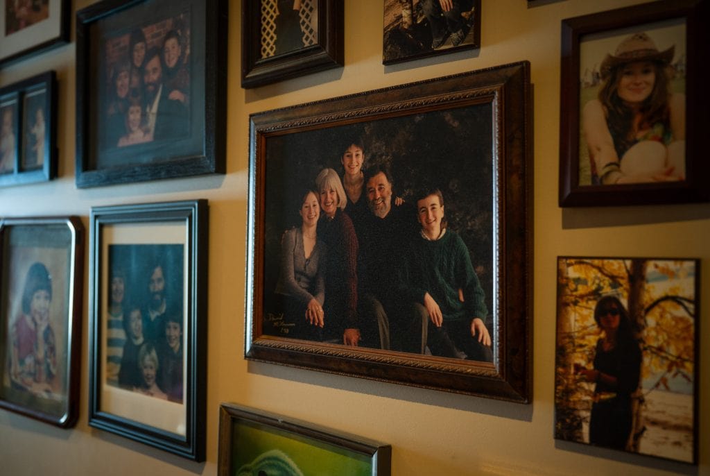 A closeup view of a family photograph hanging on a wall, surrounded by other family photos.