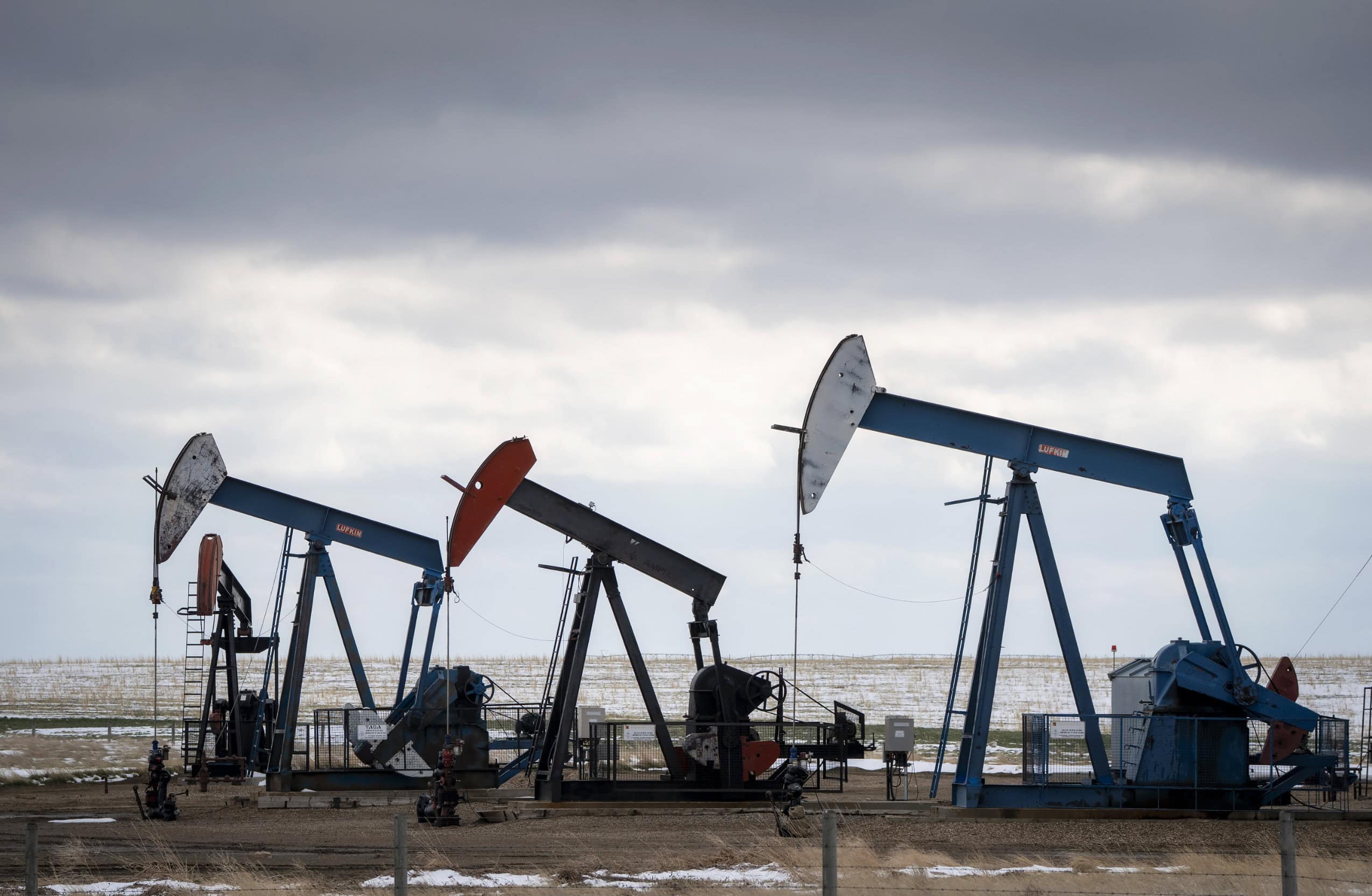 Three pump jacks in a field in rural Alberta.
