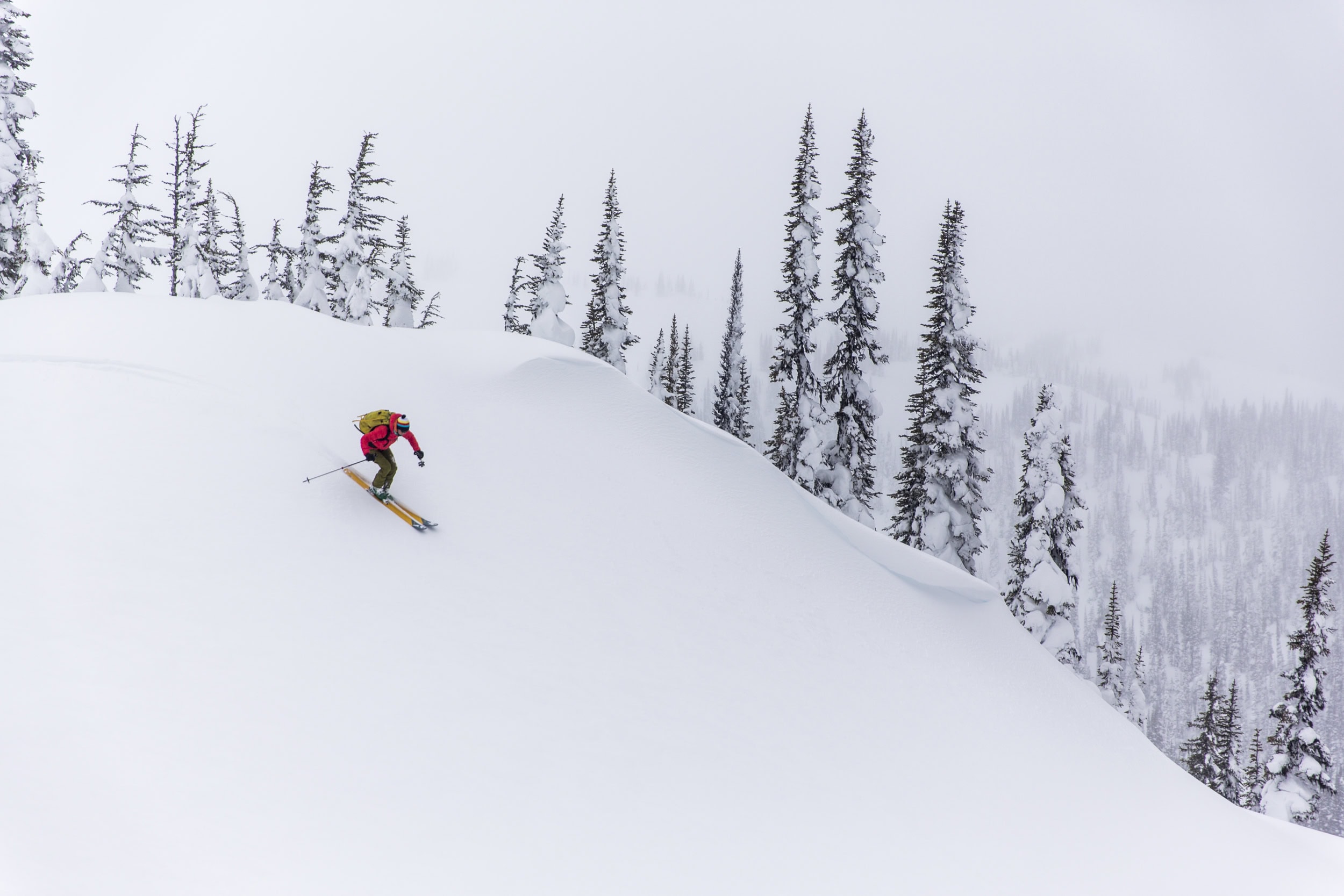 A backcountry skier descends a snowy slope.