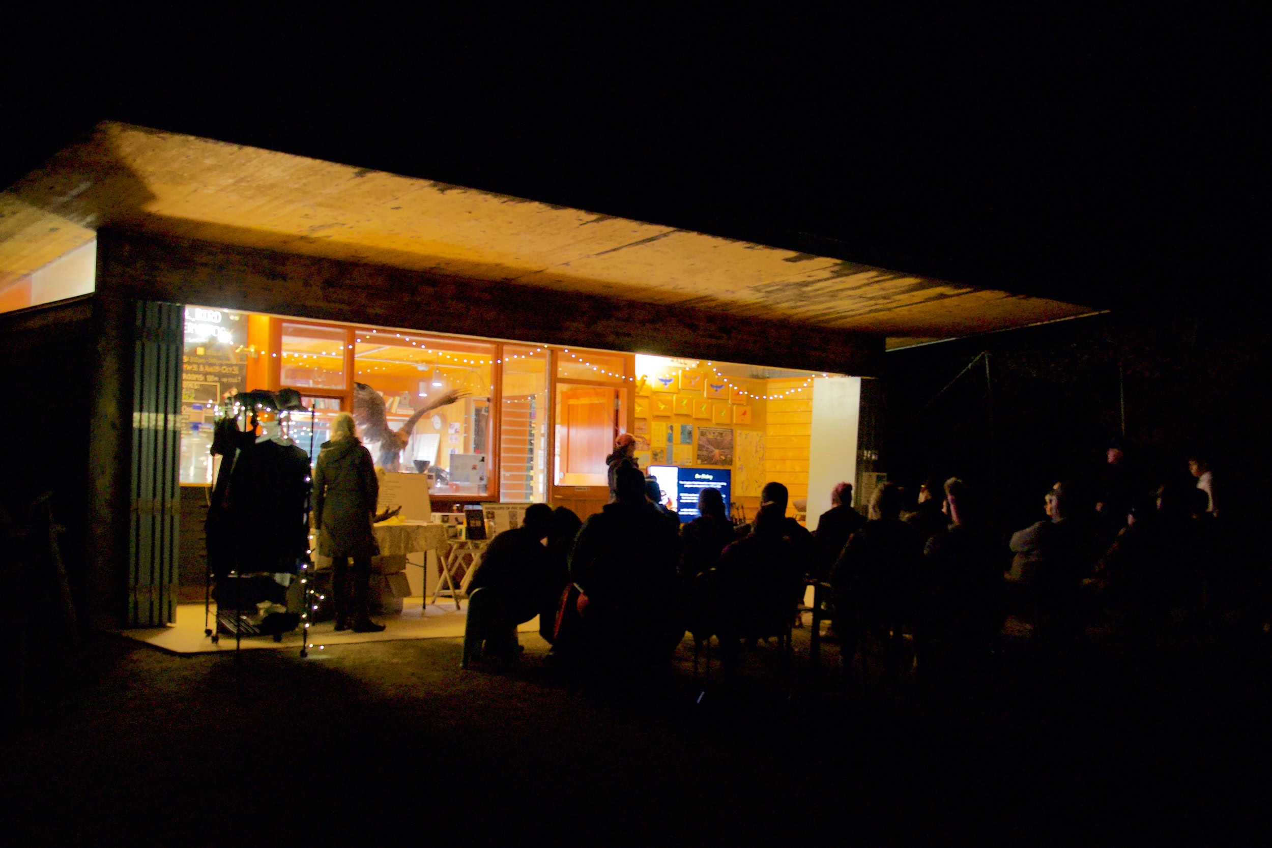 A group of people gathered in front of a building at night.