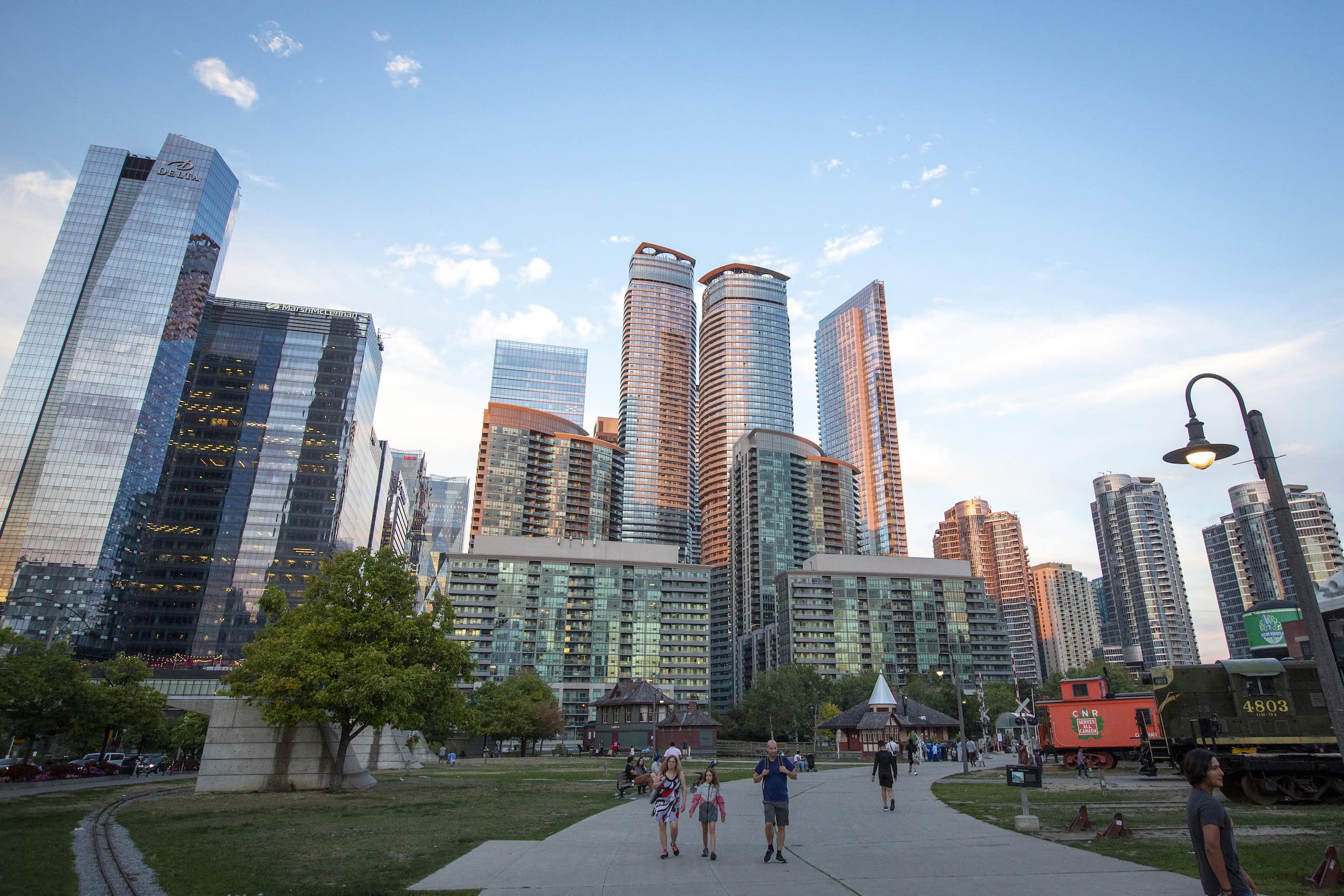 A downtown Toronto city skyline by day, with a park and wide walkway running through it.