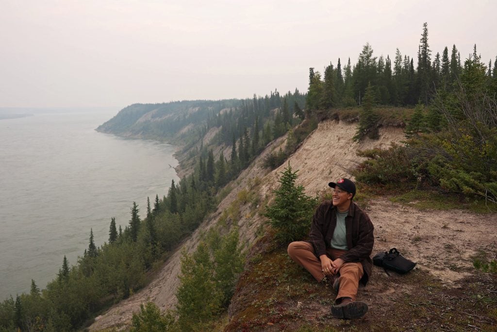 Julia-Simone Rutgers, a journalist at The Narwhal, sits along the bank of the Nelson River on a smoky evening.