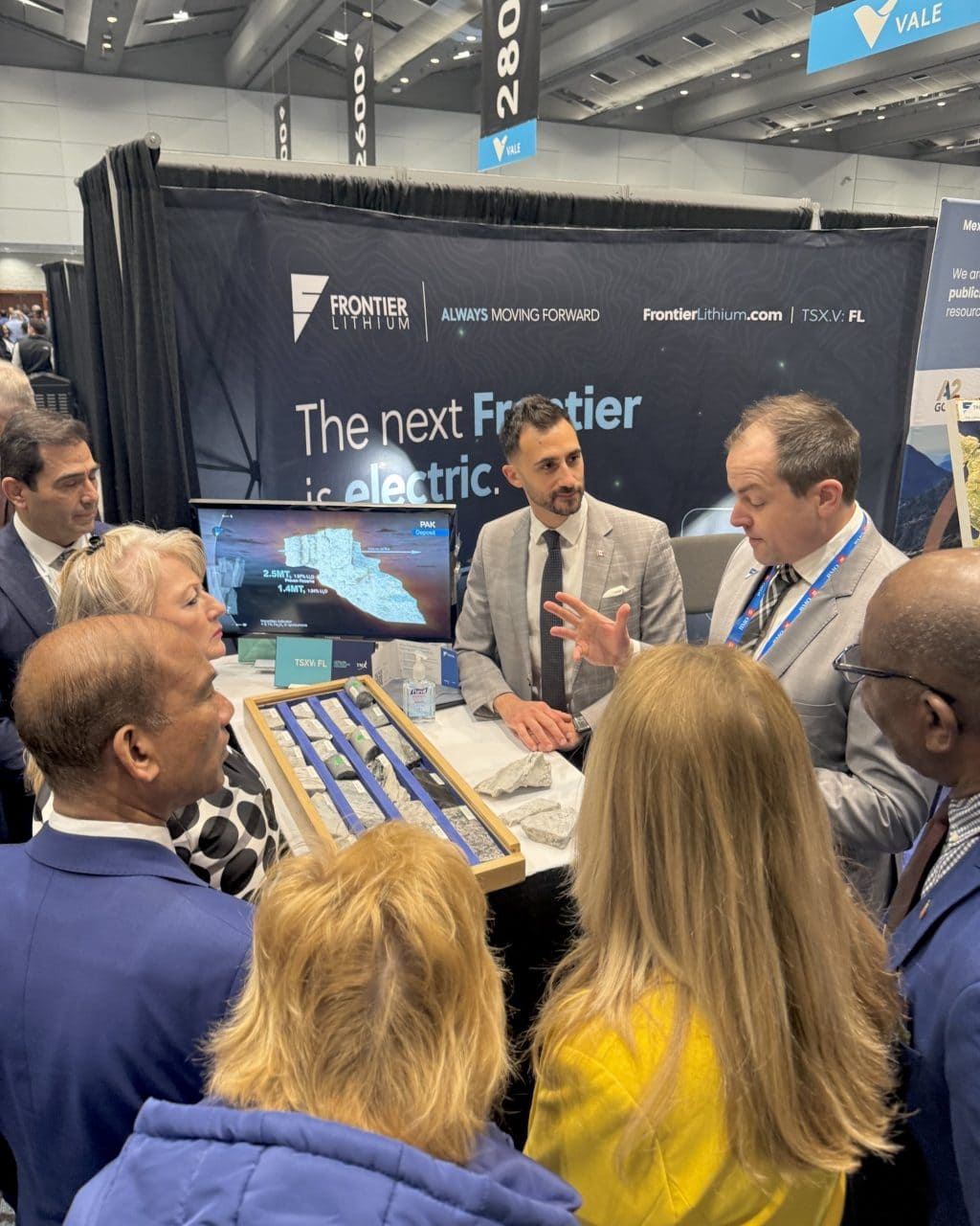 Ontario Minister of Energy and Mines Stephen Lecce listens to a speaker in a small group at the Frontier Lithium booth at the Prospectors and Developers Association of Canada's 2026 conference.