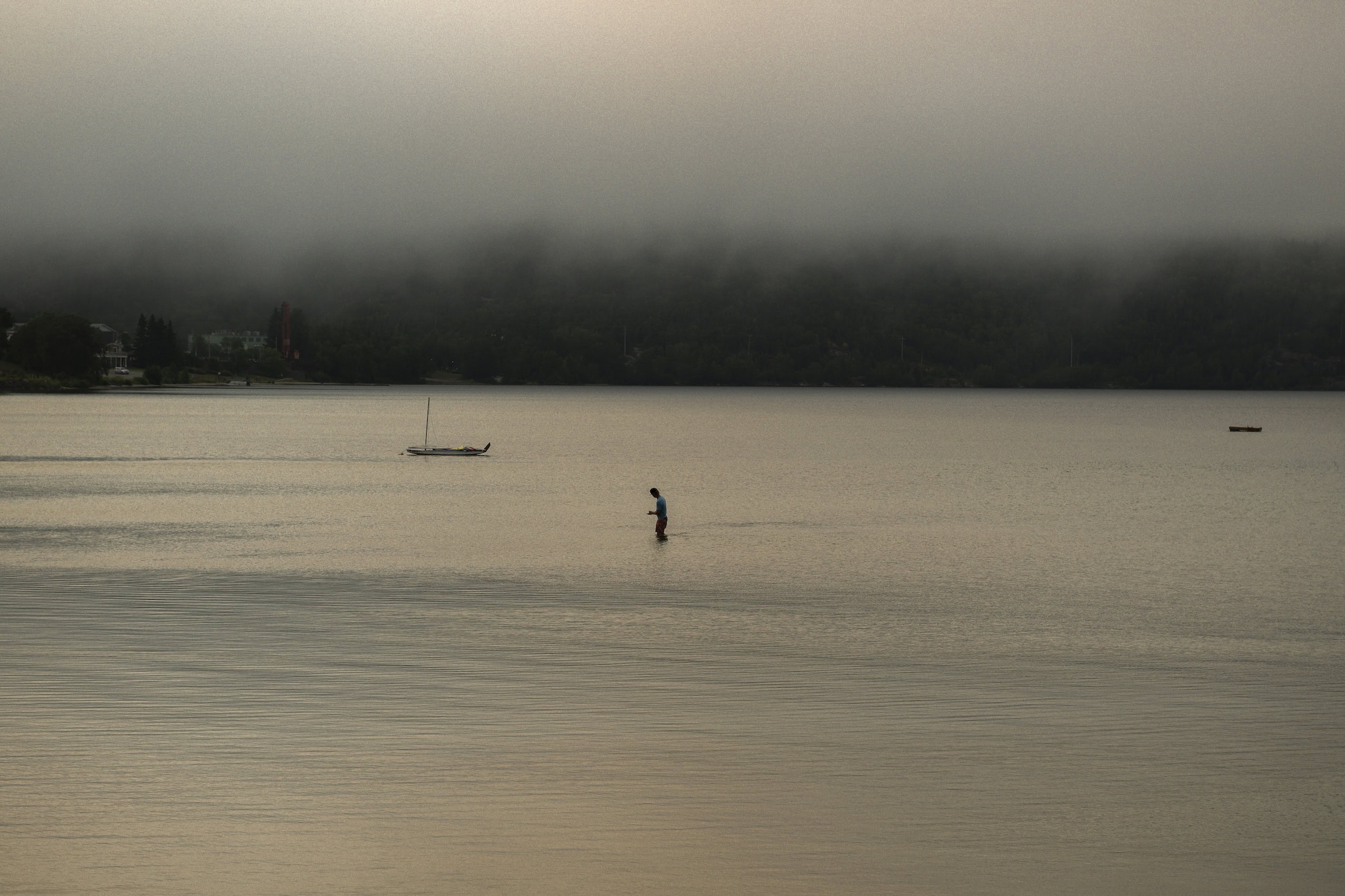 Seen from a distance, a man wades into Wawa Lake in Wawa, Ont.