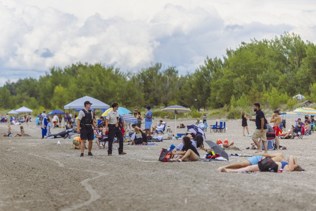 Ontario Parks employees patrol Wasaga Beach as vacationers loll about in the sand.