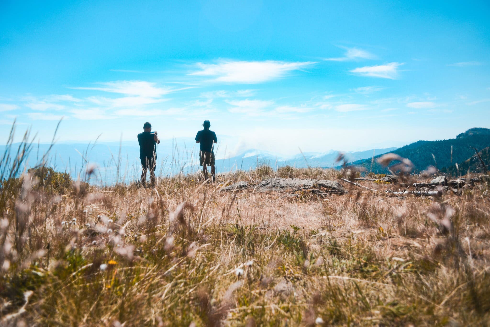 Two people look off into the distance with mountains in front of them.
