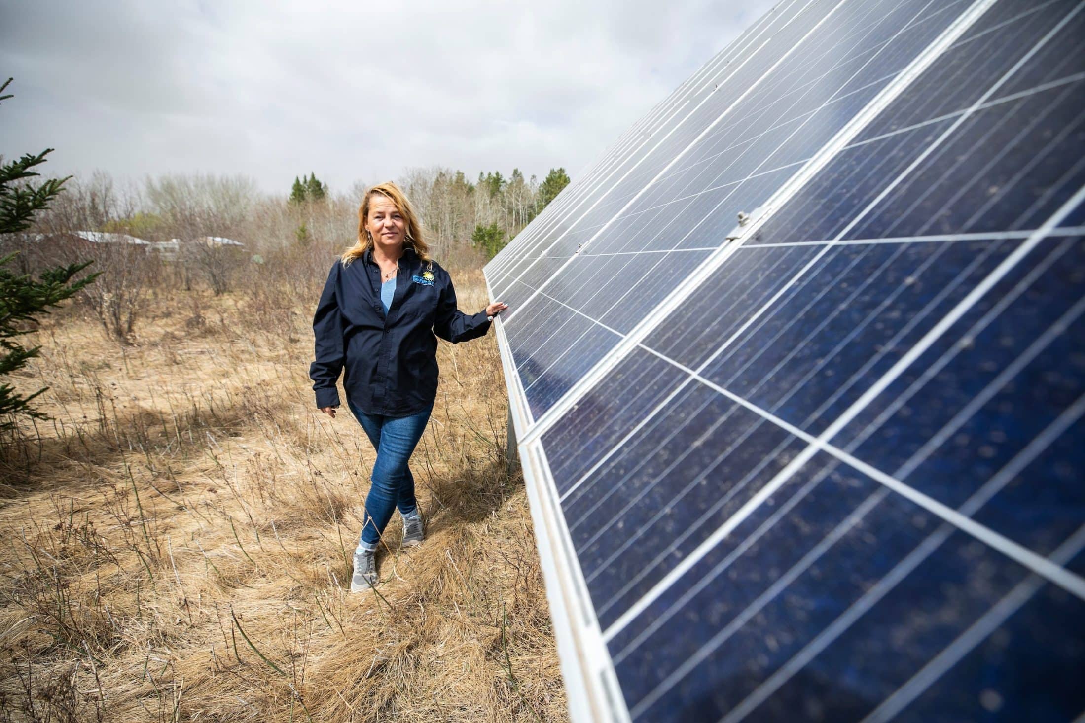 A woman places a hand on a large solar panel in a field