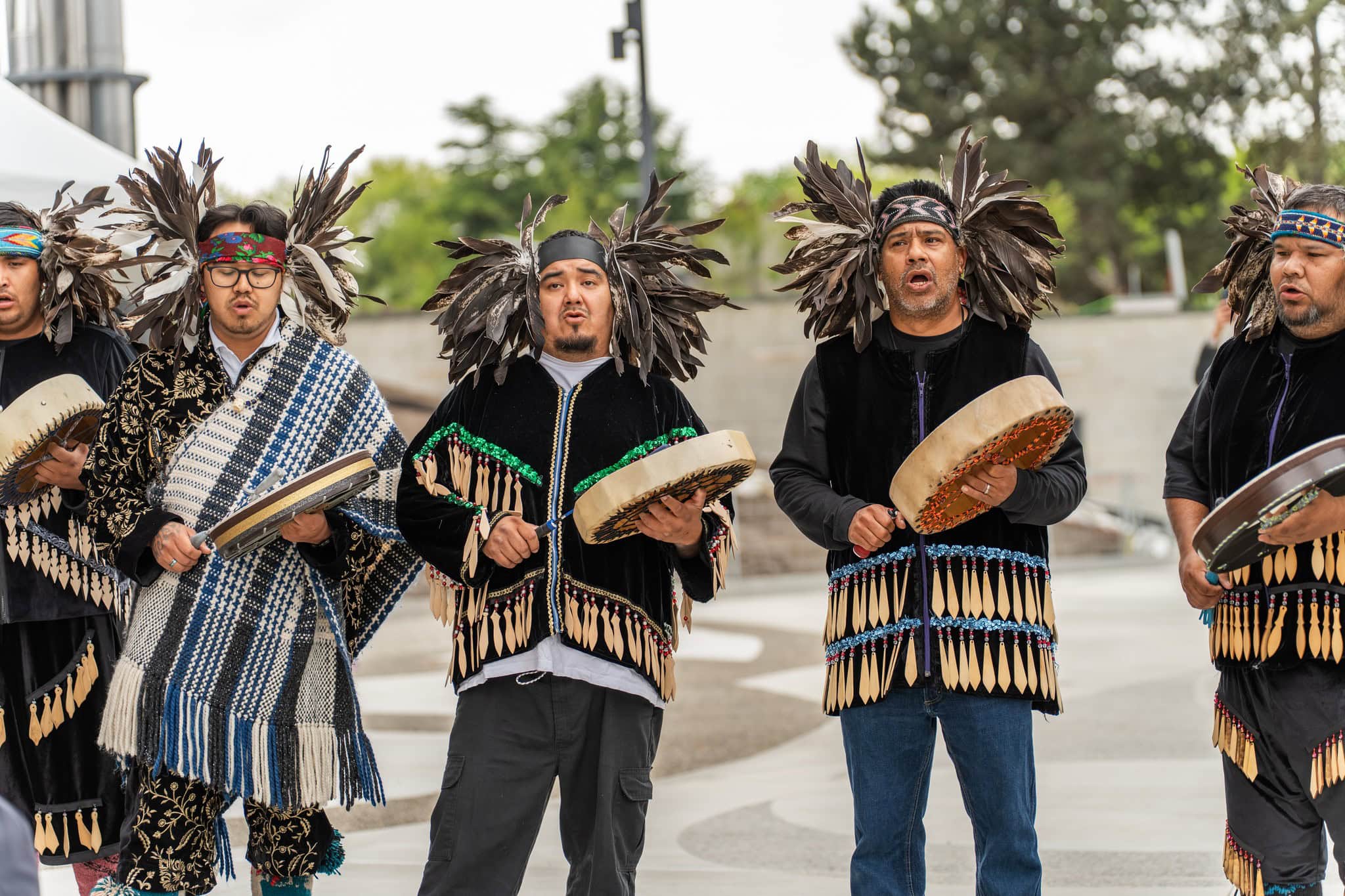 Squamish drummers sing wearing traditional regalia.