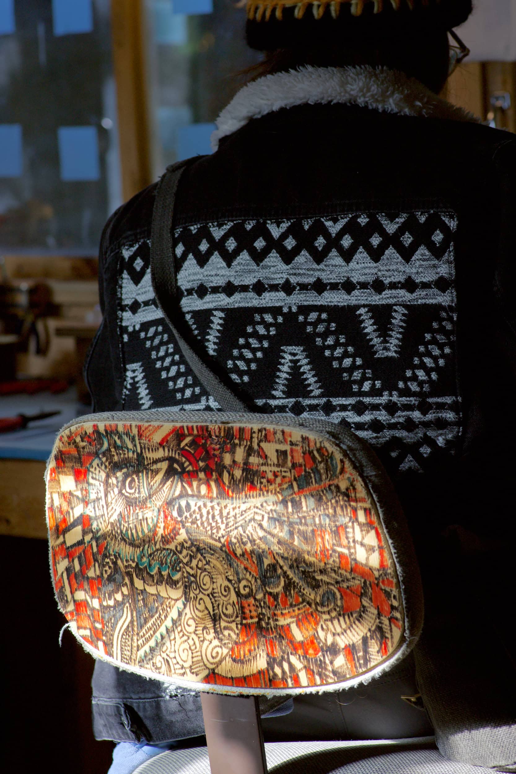 A person's back against a chair with an intricate pattern on it.