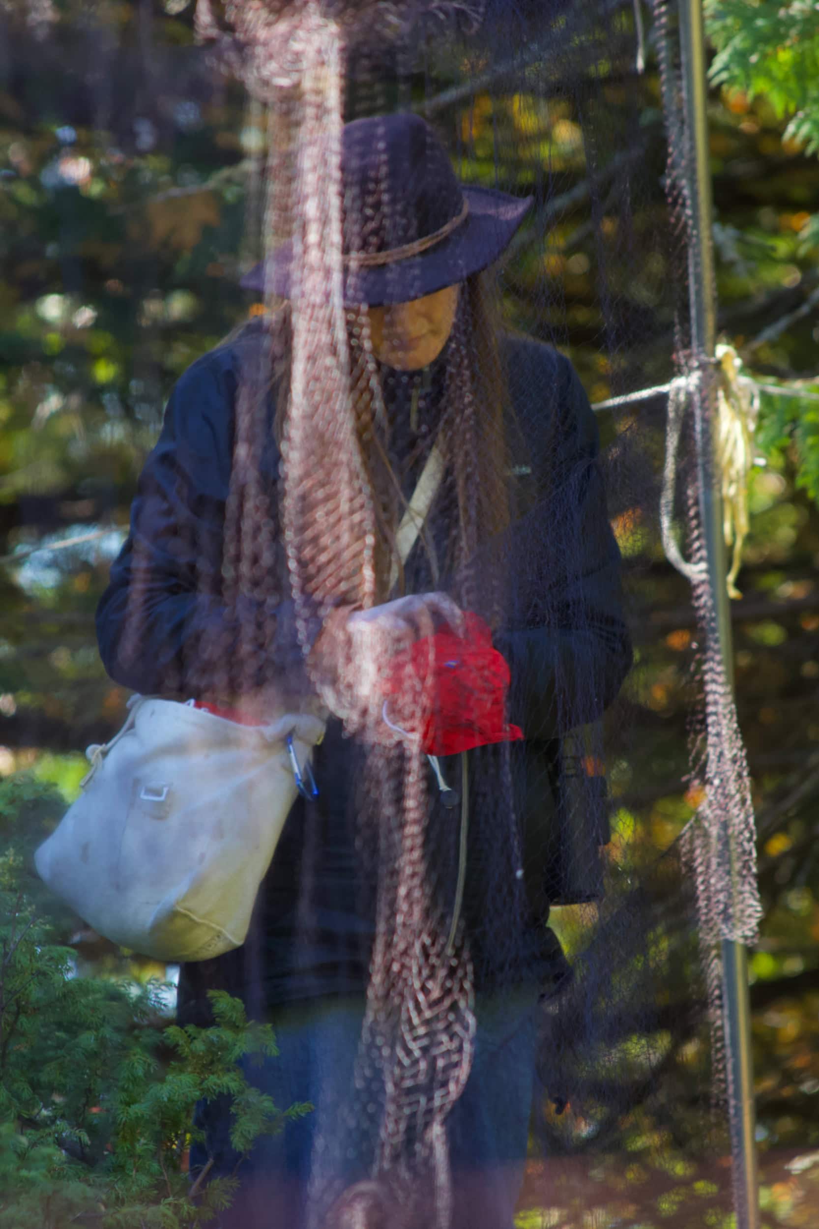 A woman standing behind a net, holding a bird wrapped in a bright red cloth.