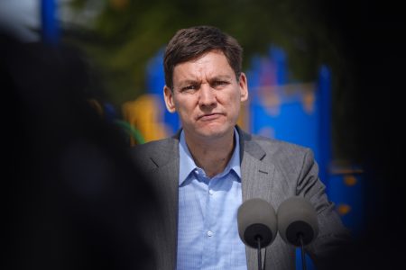 B.C. Premier David Eby pauses while speaking into a microphone.