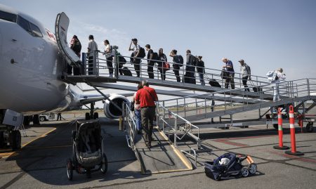 A group of people lined up on the boardwalk to board an airplane.