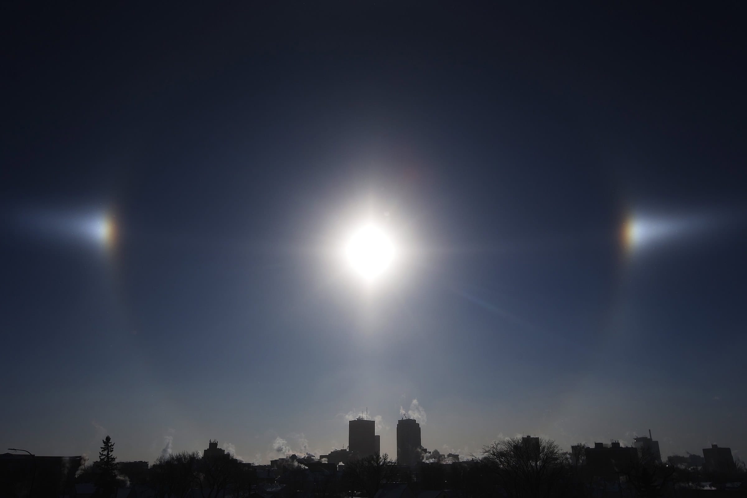 Sun Dogs, formed by the sun reflecting off ice crystals in bitterly cold temperatures, sit over the Winnipeg skyline 