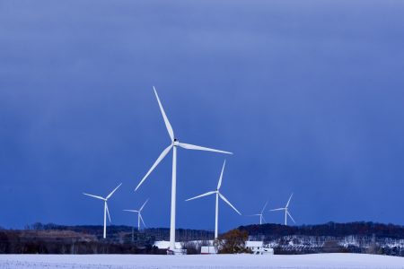 Several white wind turbines stand tall against a vibrant blue sky.