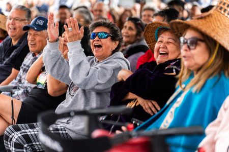 Squamish people are gathered in laughter, seated in rows.