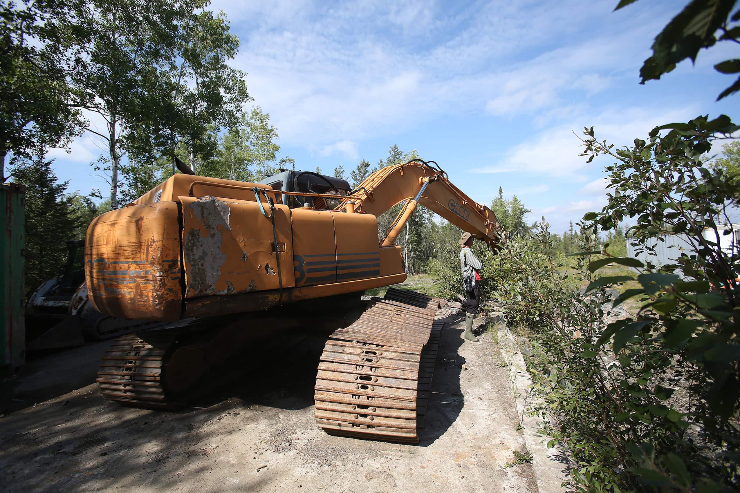 A heavy tractor extracting earth from a forested area.