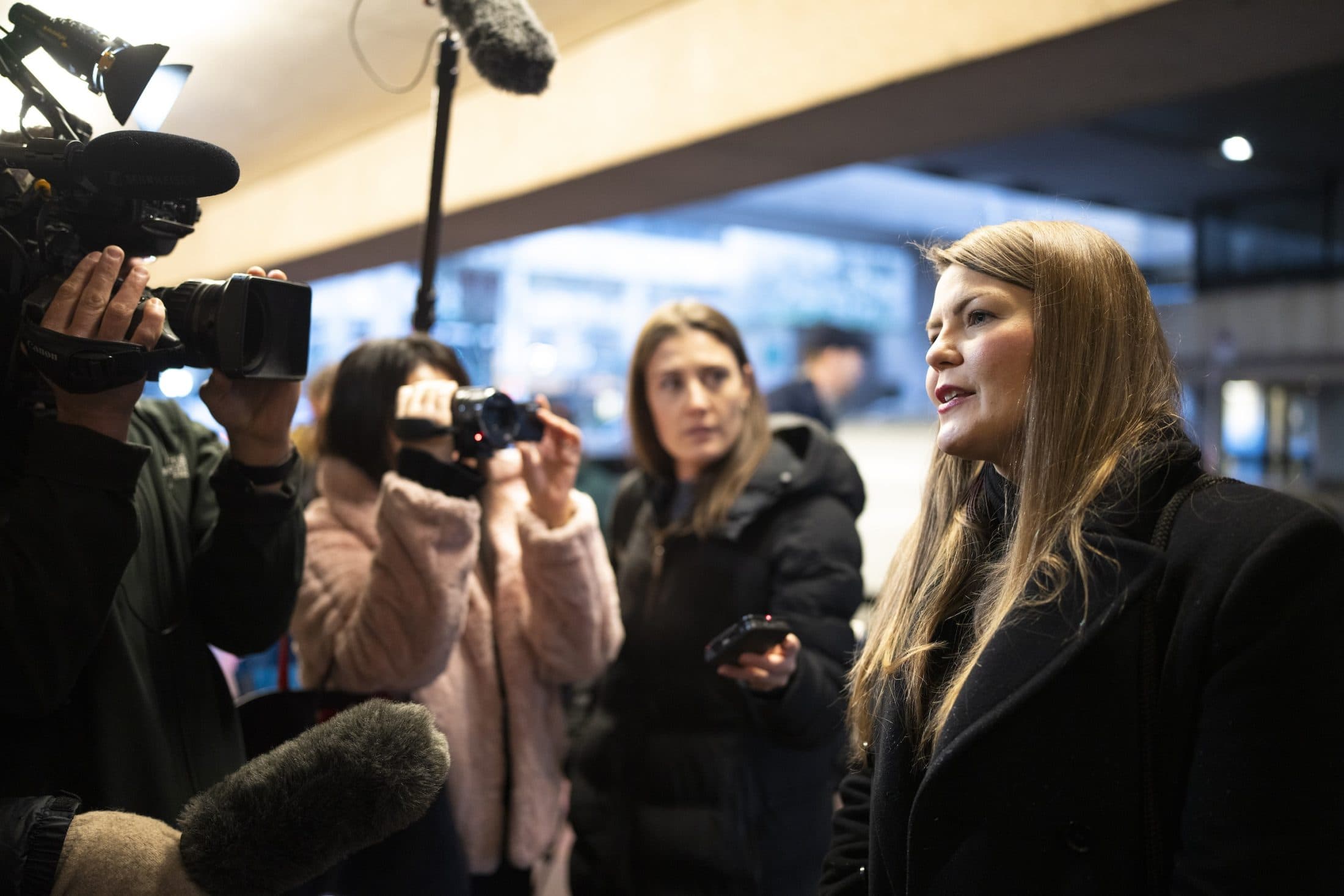 Amber Bracken speaks in front of journalists with cameras and microphones