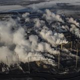 Seen from above, an oil and gas plant in Alberta billows smoke out of smoke stacks.