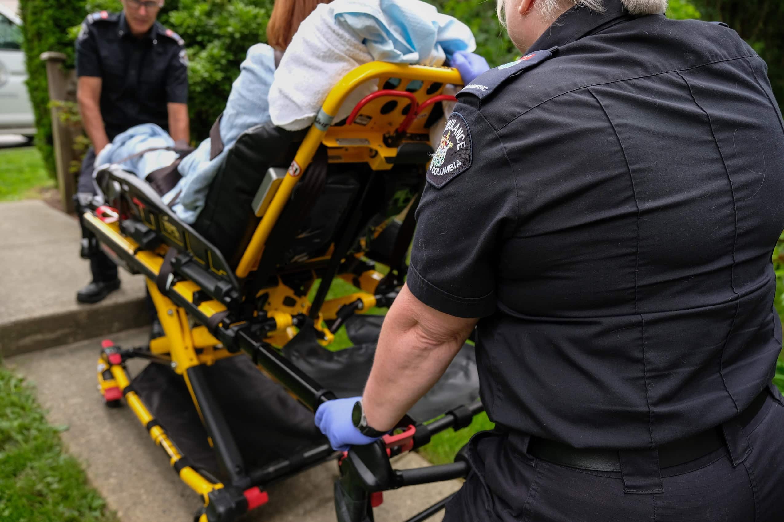 Two paramedics wheel a stretcher with a patient on it.