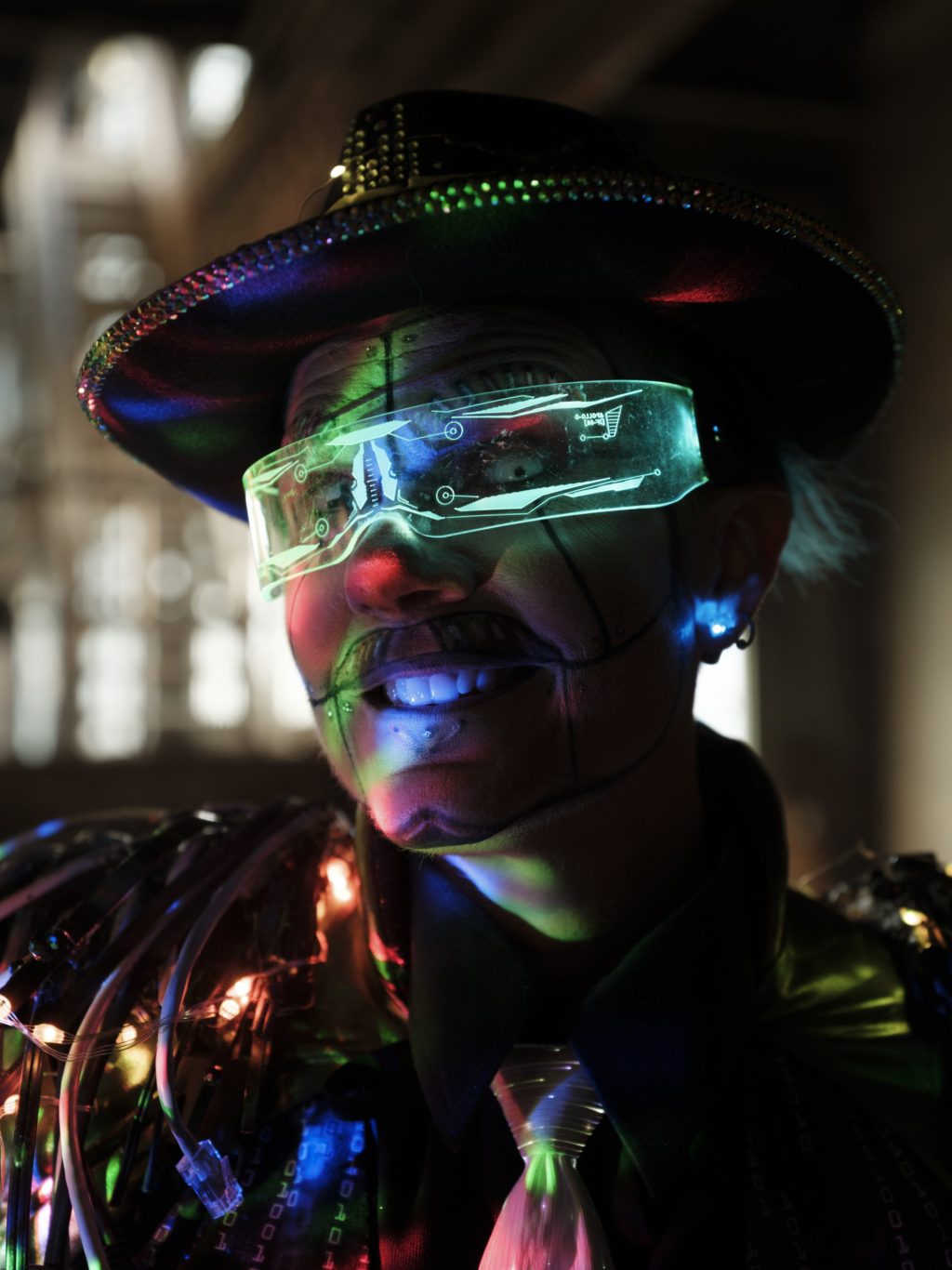 Drag artist Justin Abit stands for a photo, with multicoloured lights and computer cables adorning his clothing.