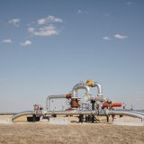 Oil and gas infrastructure in a rural field under a blue, mostly cloudless, sky in Dawson Creek, B.C.