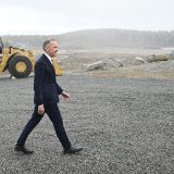 Canadian Prime Minister Mark Carney walks through a light rain at an industrial site.
