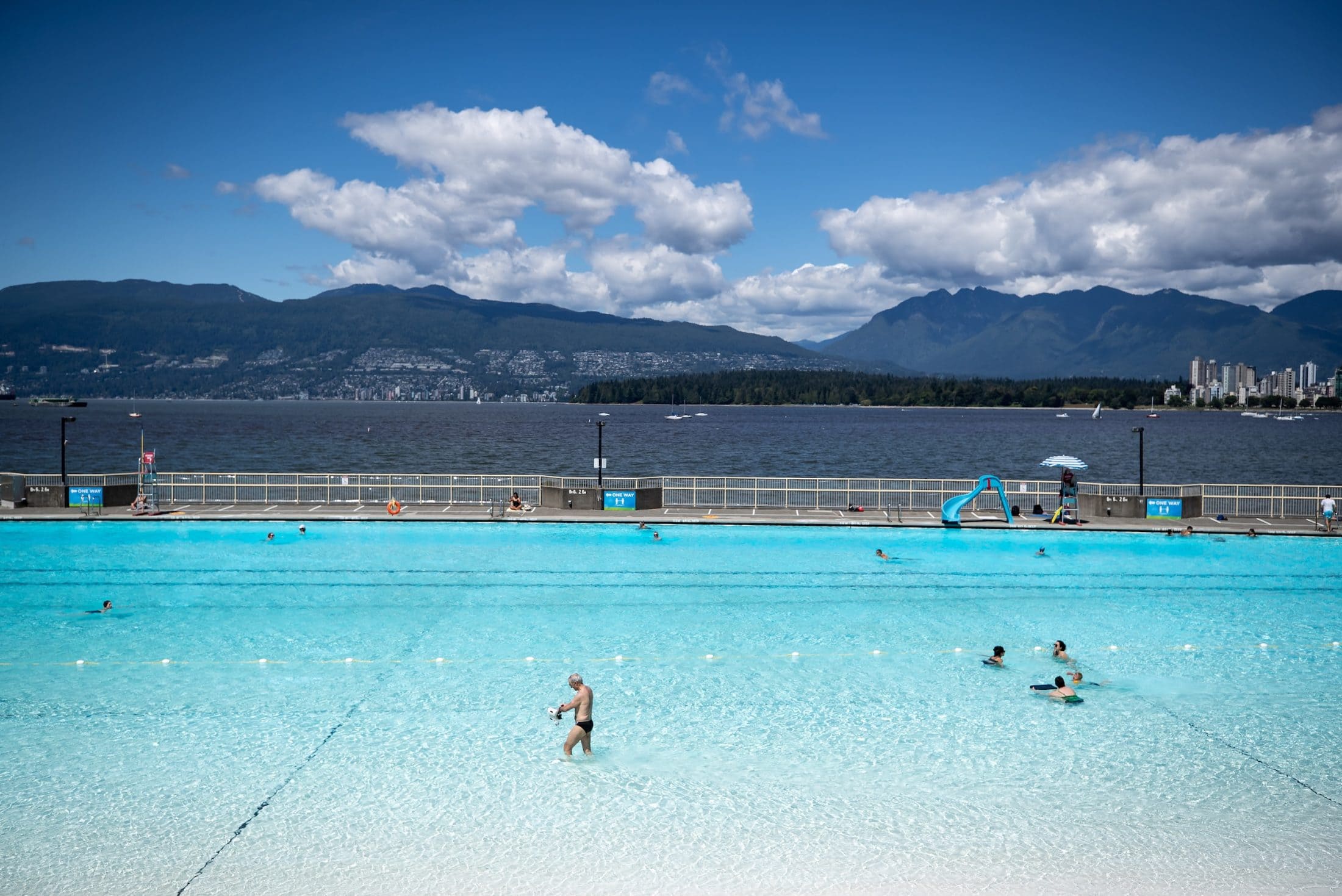 A man walks in the water as others swim at Kitsilano Pool in Vancouver.