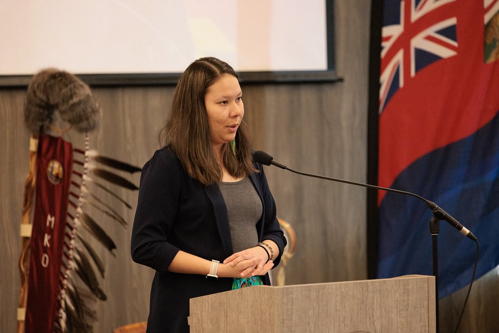 A woman speakts at a podium at a public meeting.