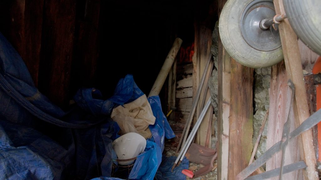 A bunch of stuff sits at a mine entrance including a clue tarp and white hard hat