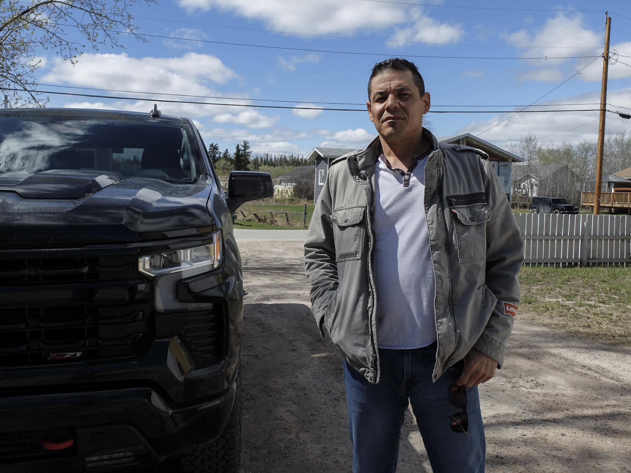 A man stands next to a car, looking into the camera.