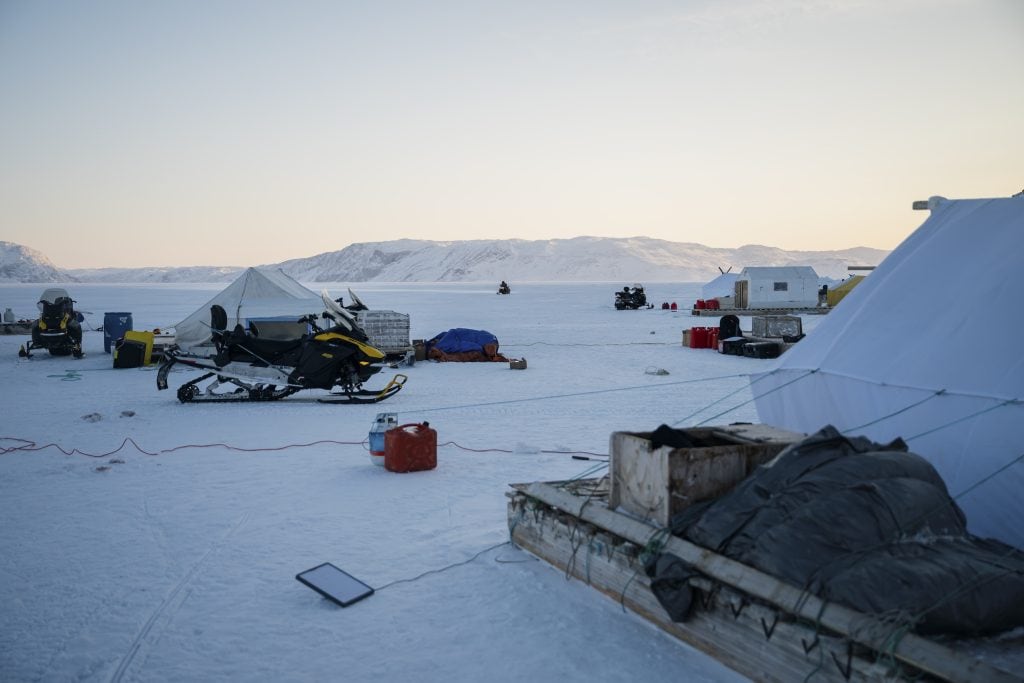 An Arctic campsite, including tents, snowmobiles, water bottles, gasoline tanks and other essentials.