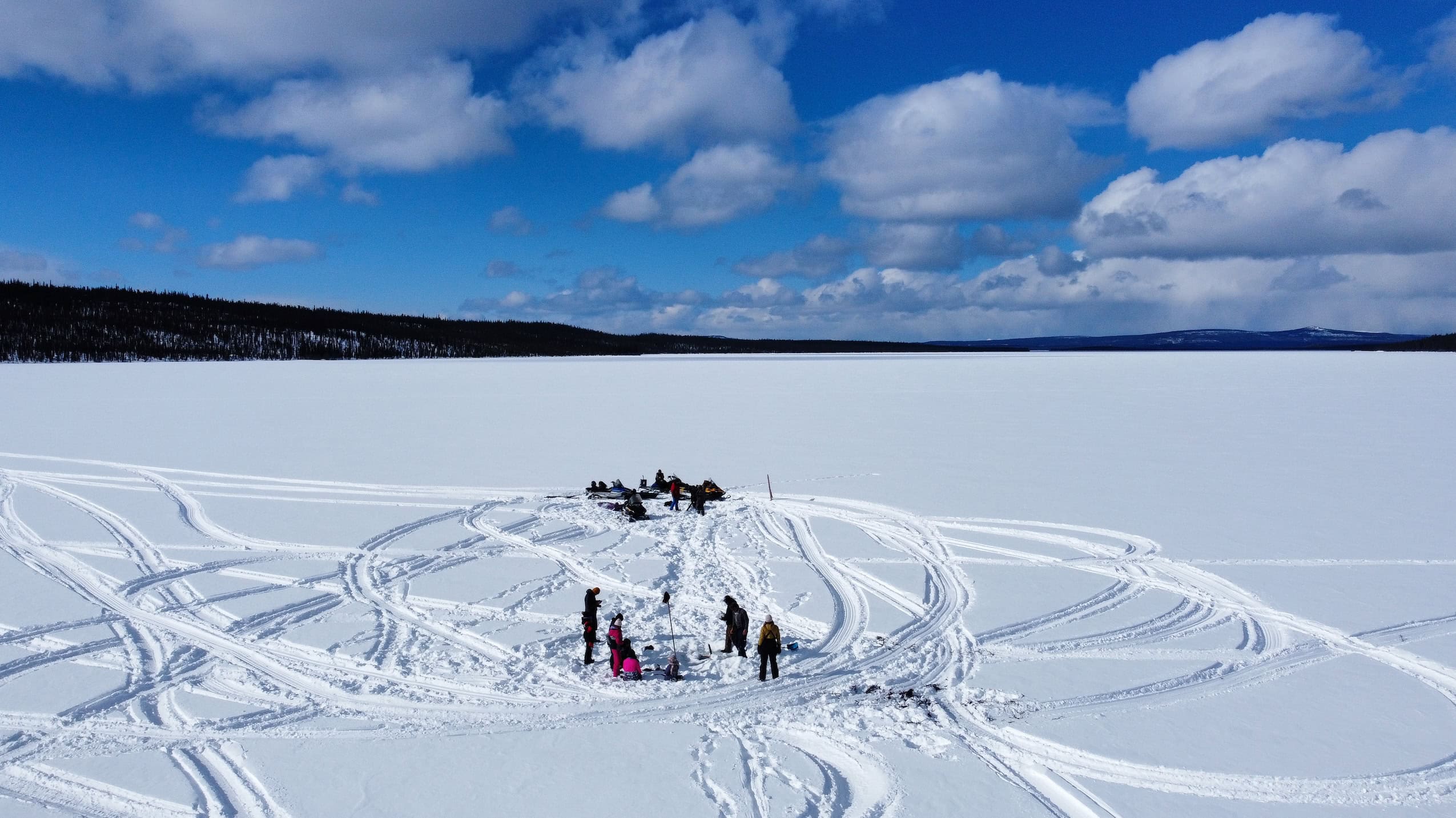 An aerial view of a group of people fishing on an ice-covered body of water.