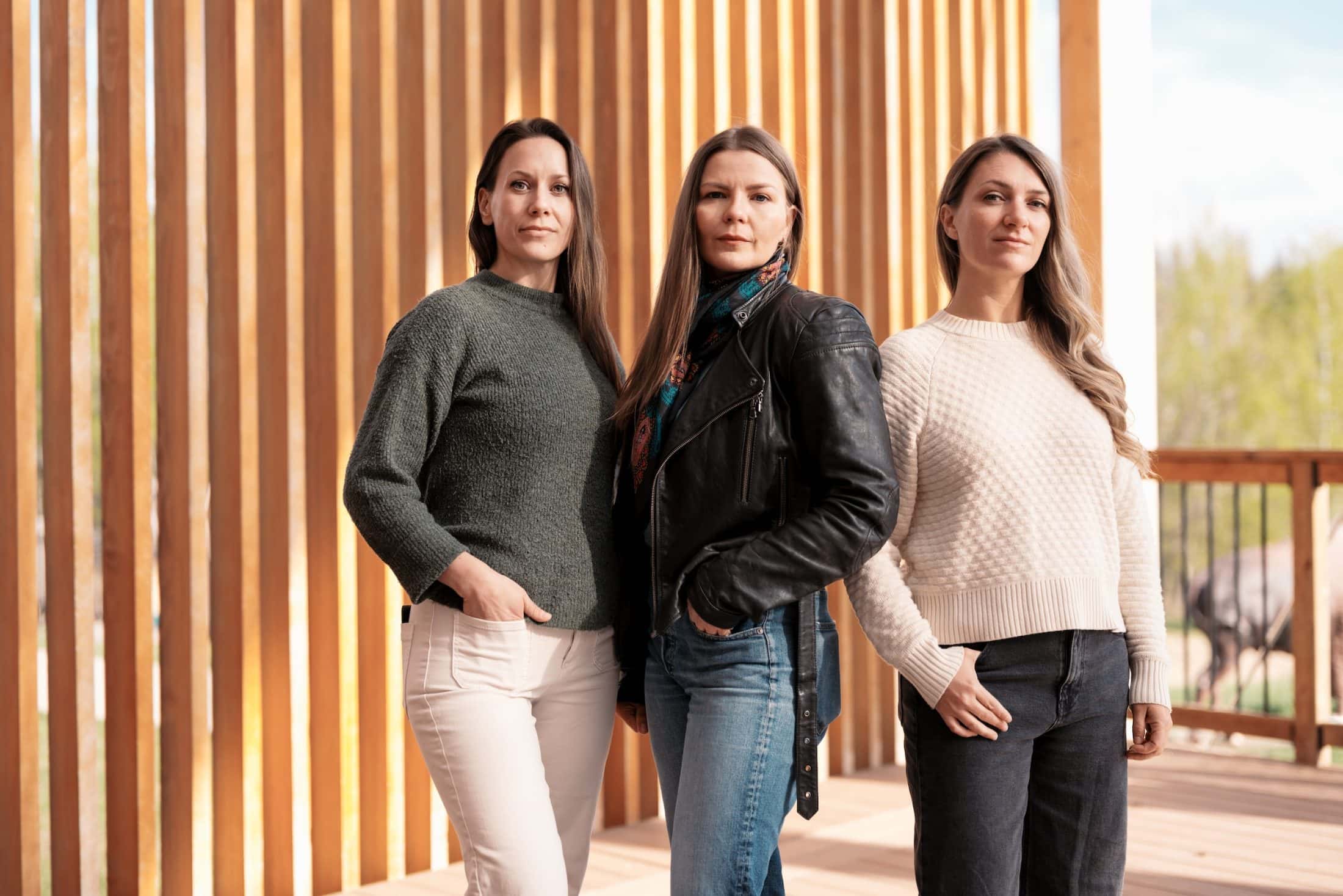 Caroll Linnitt, Amber Bracken and Emma Gilchrist stand side-by-side in front of a wood-clad building