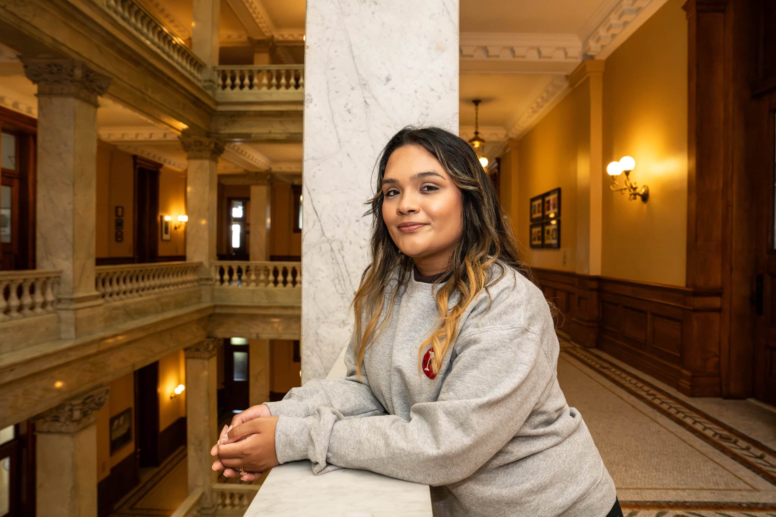 Reporter Rajpreet Sahota poses for a photo inside Queen's Park, wearing a grey sweatshirt with The Narwhal's logo on it.