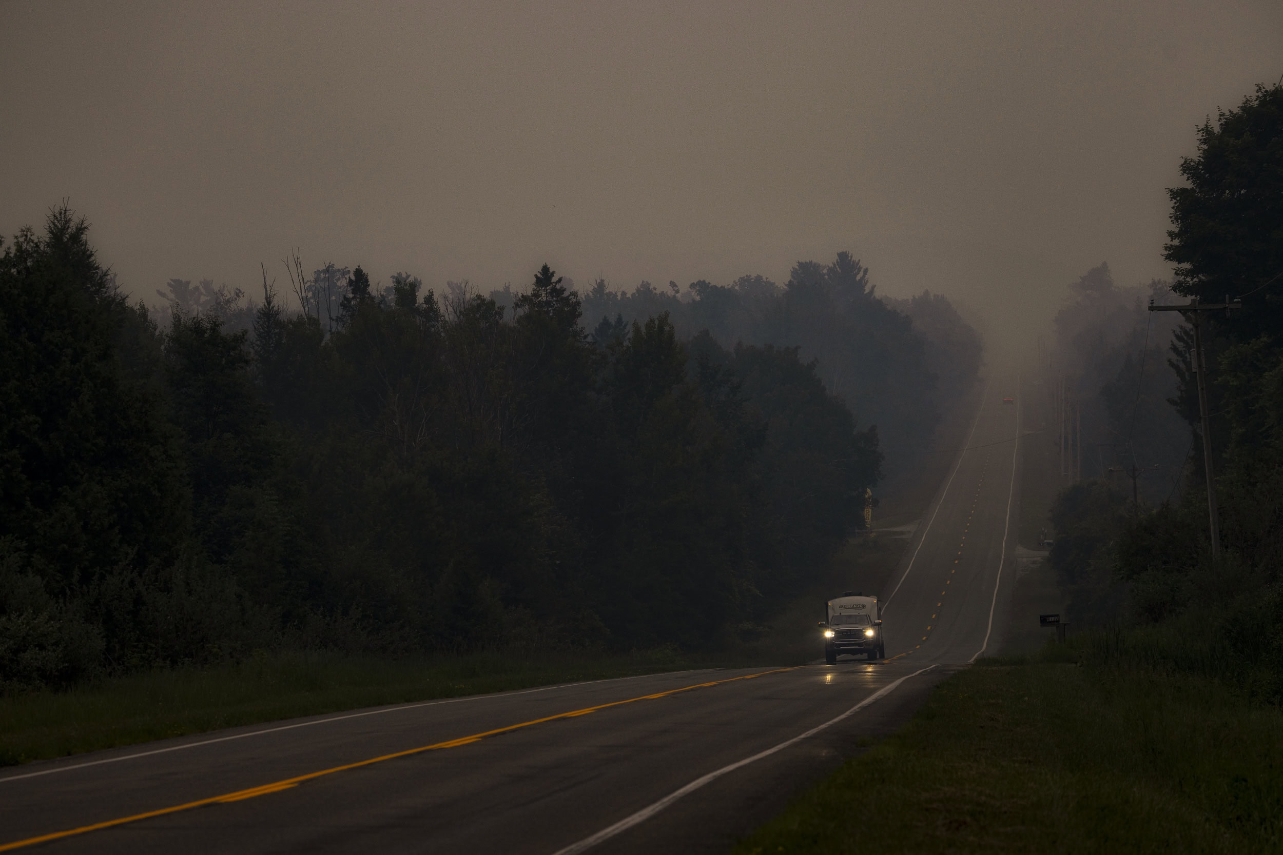 A truck drives on a road under smokey skies