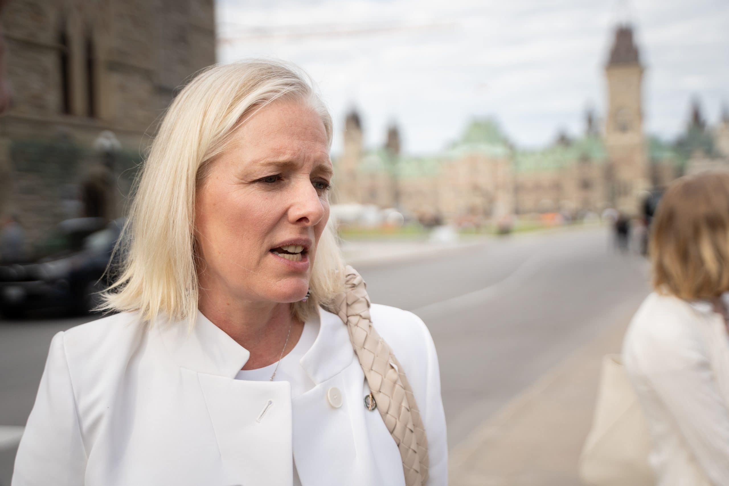 Woman in a white suit speaks on Parliament Hill in Ottawa.