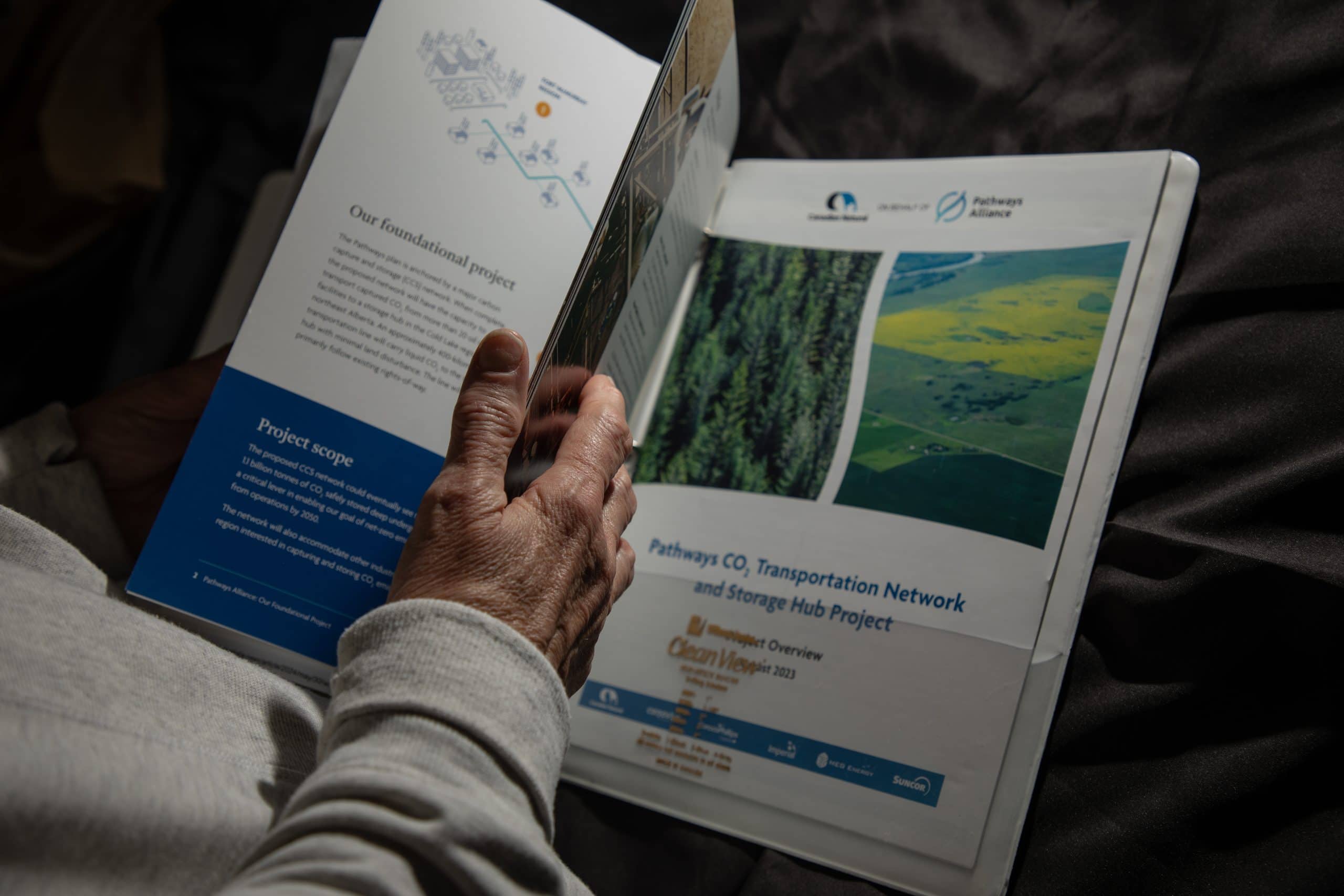 Someone's hand flips through a brochure that says "Pathways CO2 transportation network and storage hub project."