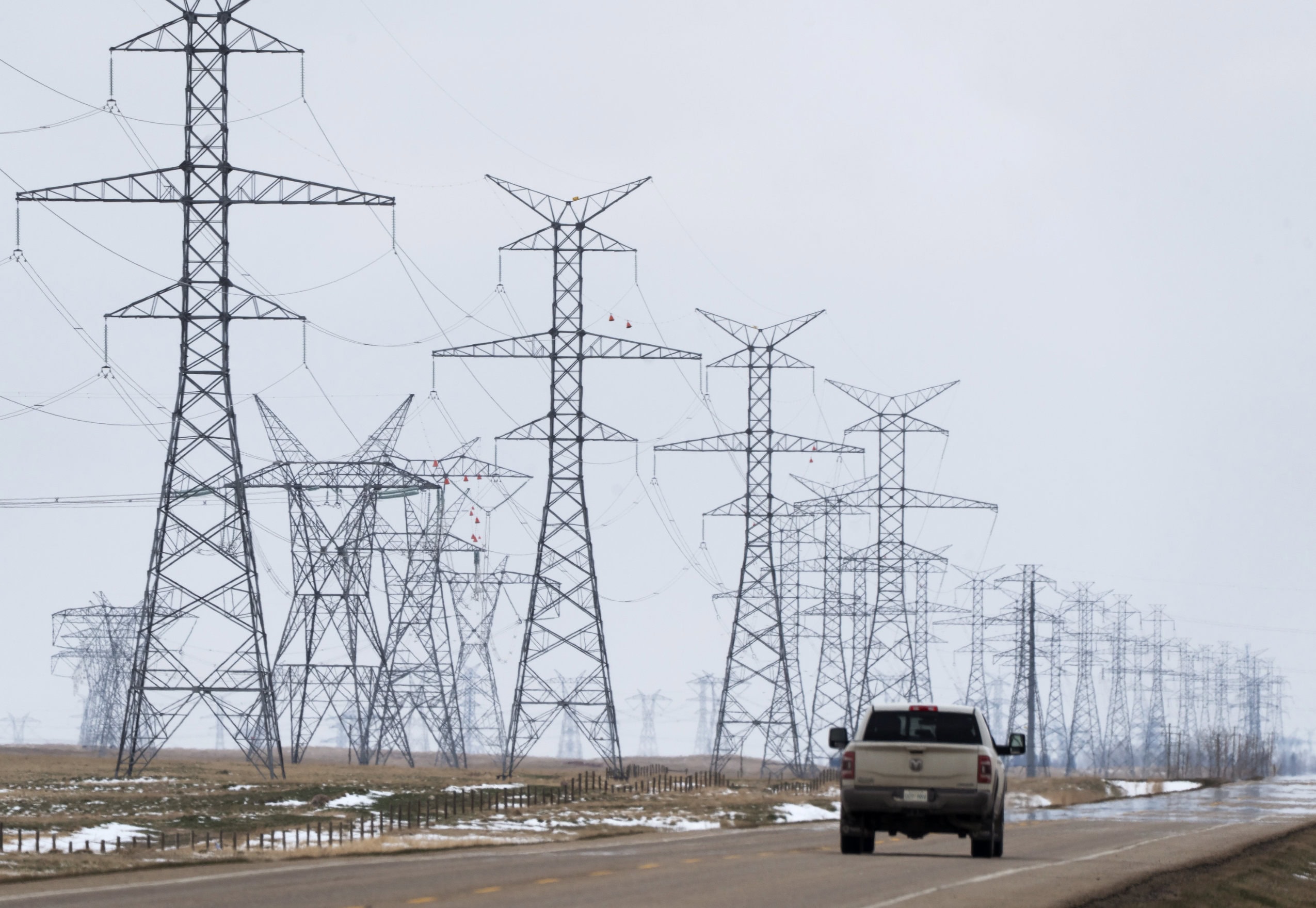 A truck drives by electricity transmission lines near Brooks, Alta., in April 2026.