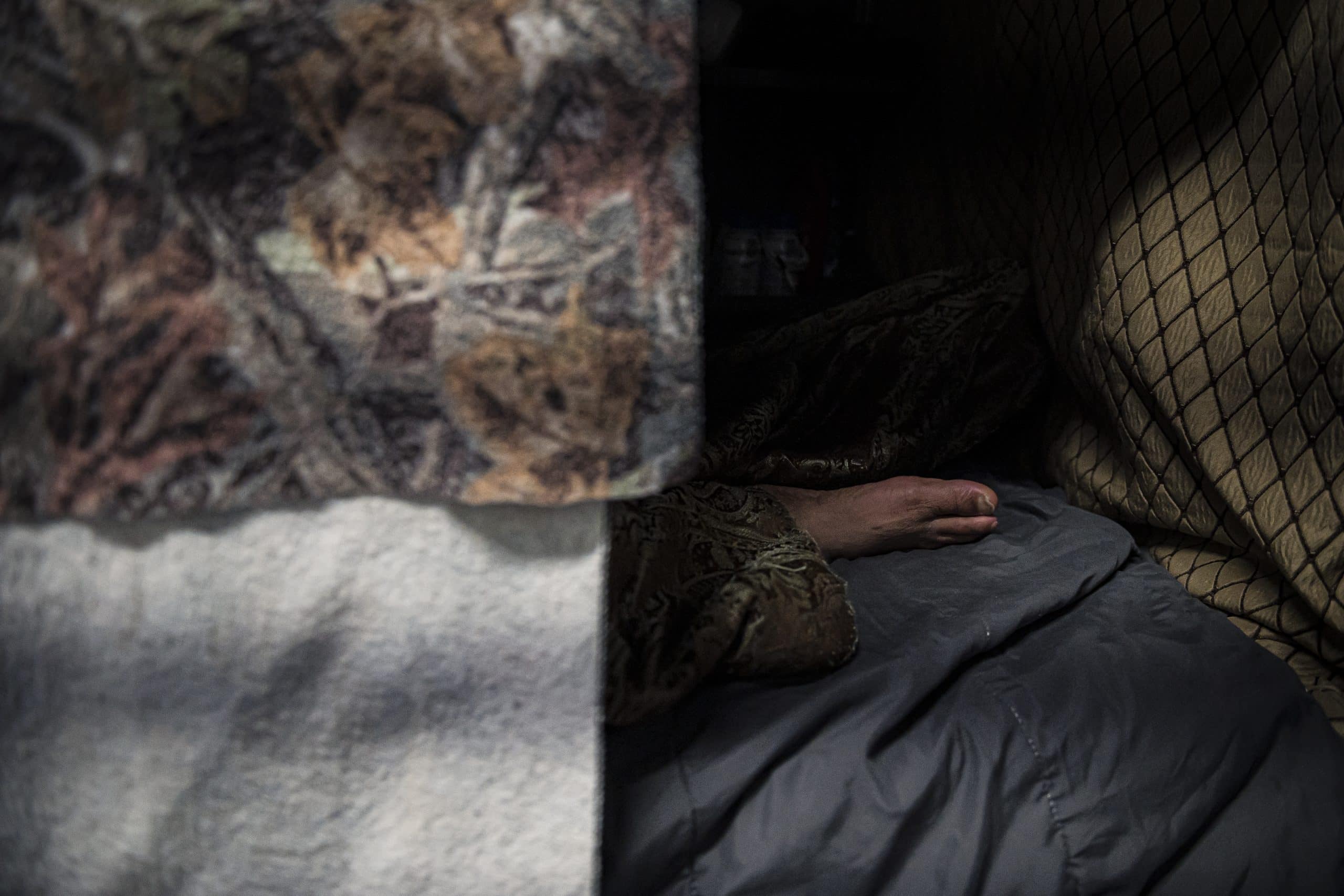 A close up of a mattress, someone appears to lay behind some cloths