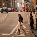 A person wearing a mask walks across a street in Toronto, as wildfire smoke blankets the city in July 2026.