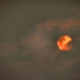 A bright orange sun is shrouded by wildfire smoke.