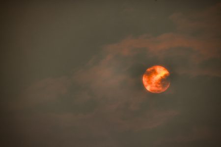 A bright orange sun is shrouded by wildfire smoke.