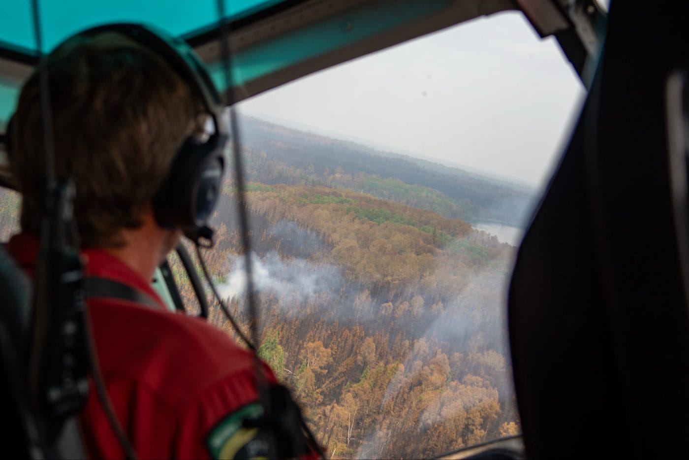 A forested landscape damaged by wildfire is seen from a helicopter.