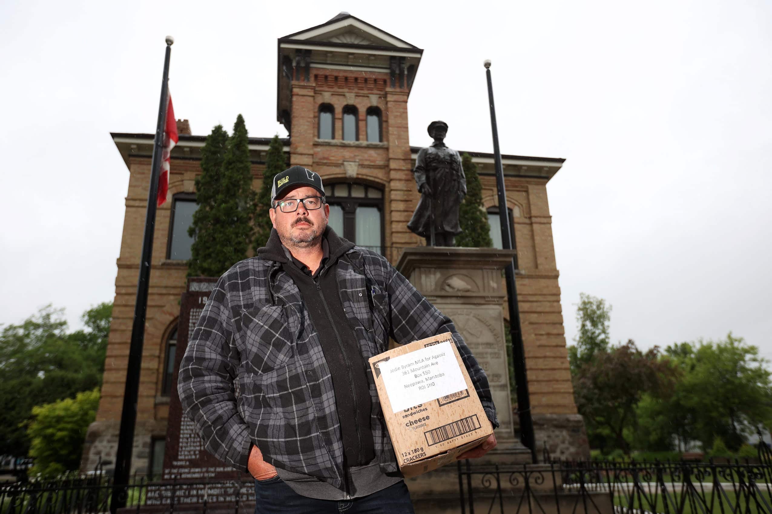 A Manitoba man poses for a photo while holding a box of letters addressed to an elected official.