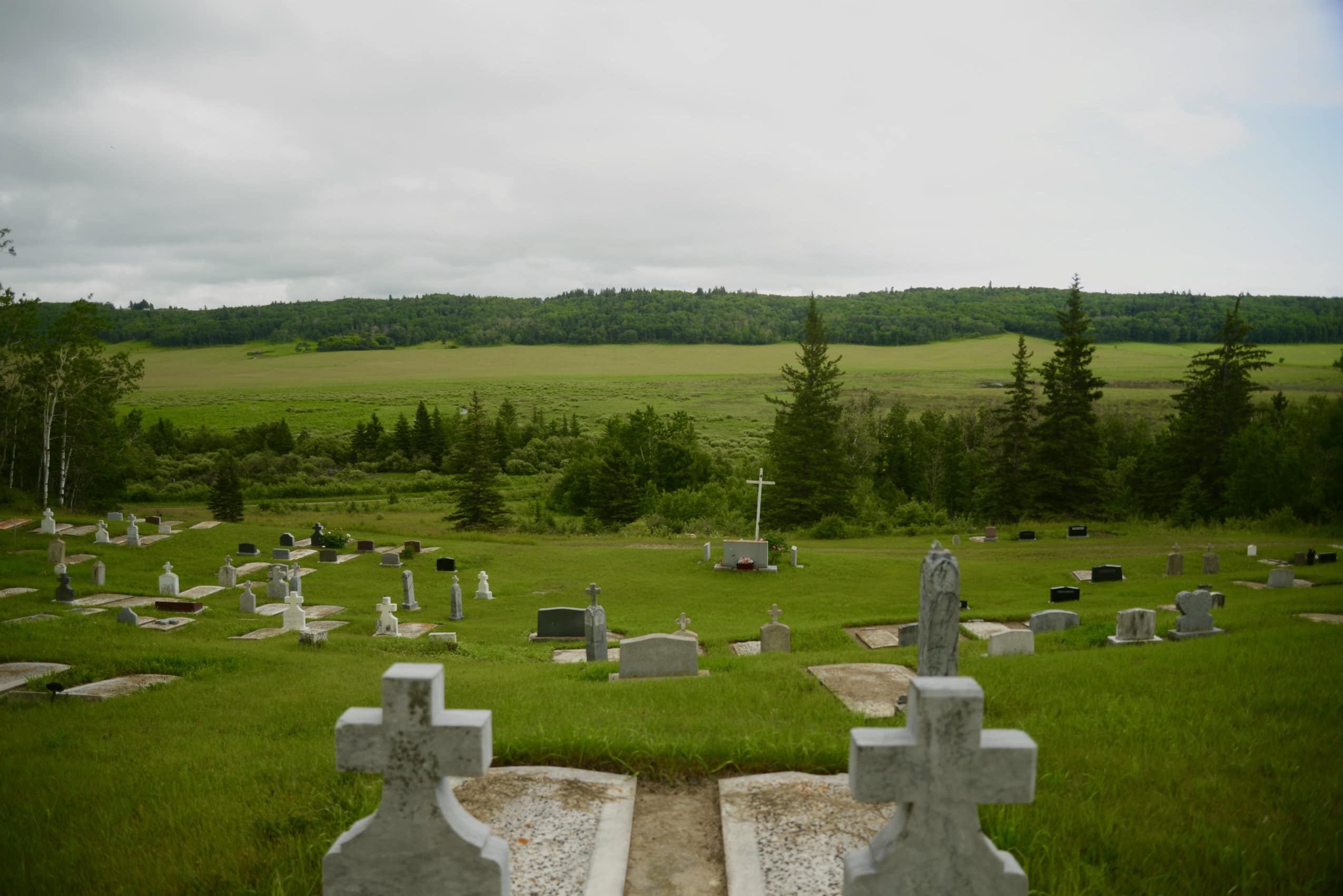 A historic cemetery in a rural area, with lush green fields in the background.