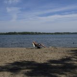 A lone sunbather in a lounge chair on a sandy beach