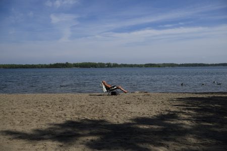 A lone sunbather in a lounge chair on a sandy beach